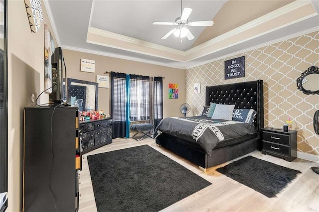 bedroom with crown molding, lofted ceiling, light wood-type flooring, and a tray ceiling