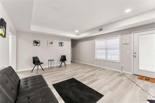 sitting room with a raised ceiling and light wood-type flooring