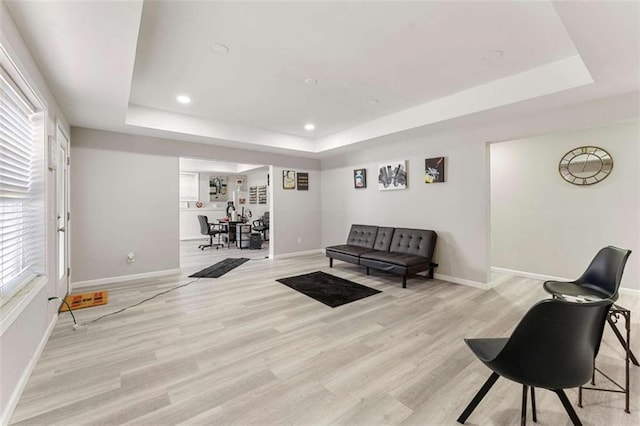 living room featuring light hardwood / wood-style flooring and a tray ceiling