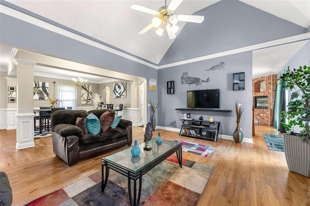 living room with high vaulted ceiling, crown molding, light hardwood / wood-style floors, and ornate columns