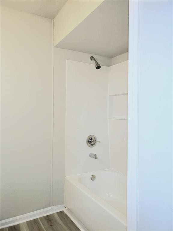 bathroom with wood finished floors, shower / tub combination, and baseboards