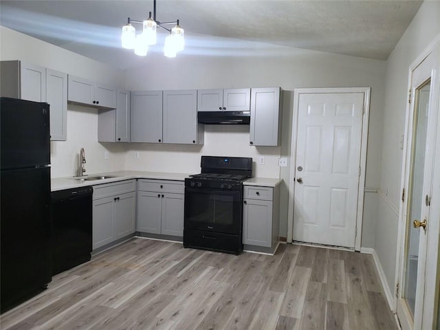 kitchen featuring light wood-style floors, under cabinet range hood, gray cabinetry, black appliances, and a sink