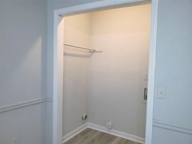 clothes washing area featuring laundry area, electric dryer hookup, baseboards, and wood finished floors