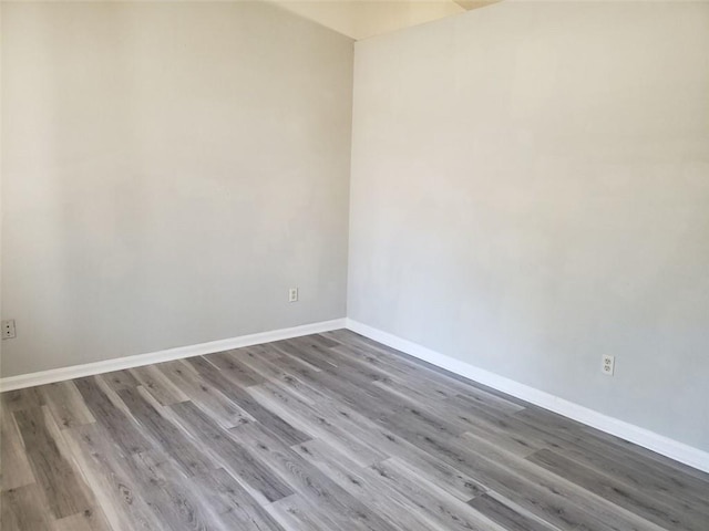 spare room featuring baseboards and wood finished floors