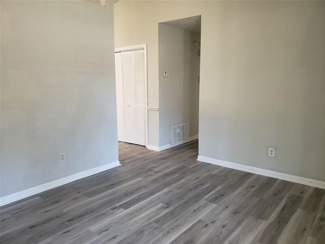 unfurnished room with baseboards, visible vents, and dark wood-style flooring