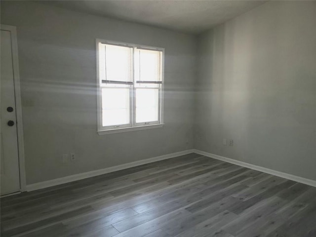 empty room featuring baseboards and dark wood-type flooring