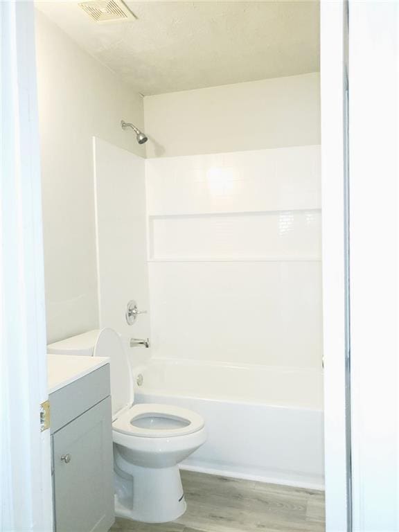 full bath with bathtub / shower combination, toilet, wood finished floors, vanity, and visible vents