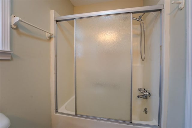 bathroom featuring shower / bath combination with glass door and toilet