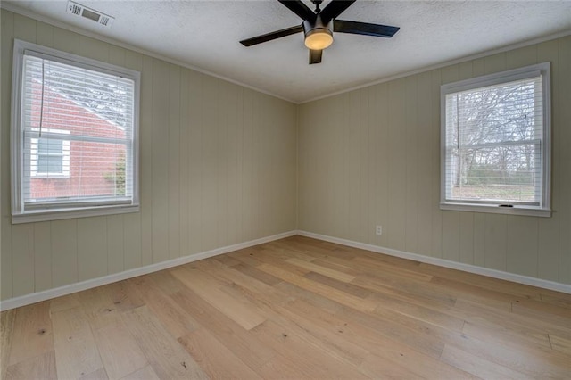 spare room featuring ceiling fan, ornamental molding, a textured ceiling, and light wood-type flooring