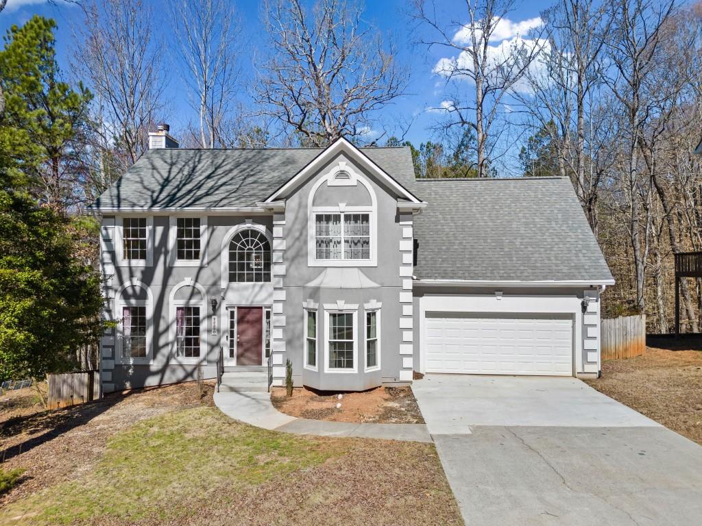 view of front of home featuring an attached garage, fence, driveway, roof with shingles, and a chimney