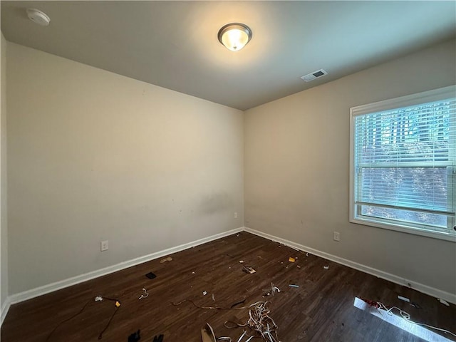 unfurnished room featuring baseboards, visible vents, and dark wood-type flooring