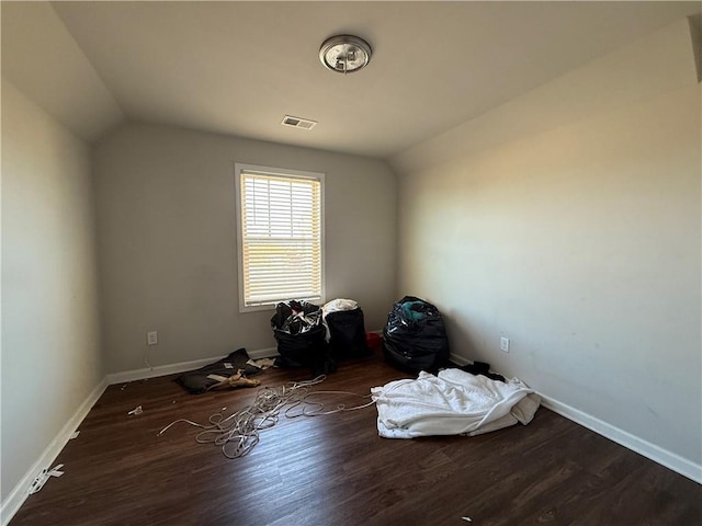 interior space with baseboards, visible vents, vaulted ceiling, and wood finished floors