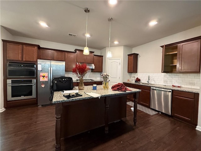 kitchen featuring open shelves, visible vents, appliances with stainless steel finishes, under cabinet range hood, and a kitchen breakfast bar