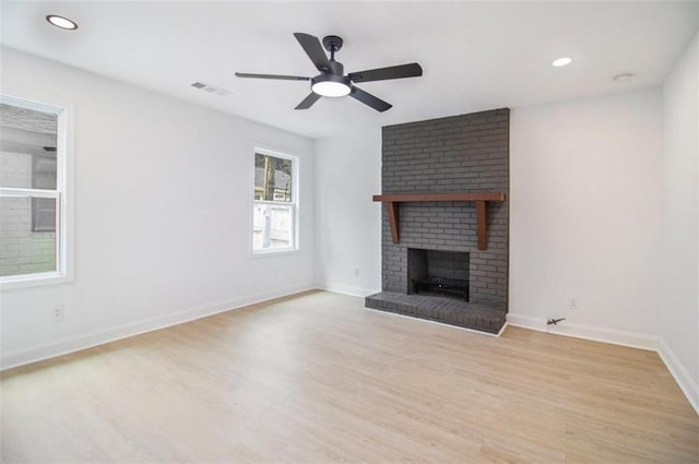 unfurnished living room with ceiling fan, a fireplace, and light hardwood / wood-style flooring