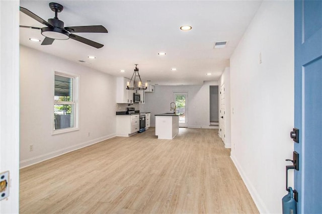 unfurnished living room with ceiling fan, sink, and light hardwood / wood-style floors