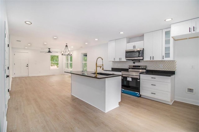 kitchen featuring appliances with stainless steel finishes, white cabinetry, an island with sink, sink, and light hardwood / wood-style floors