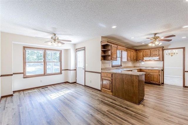 kitchen with kitchen peninsula, sink, ceiling fan, light hardwood / wood-style floors, and a textured ceiling