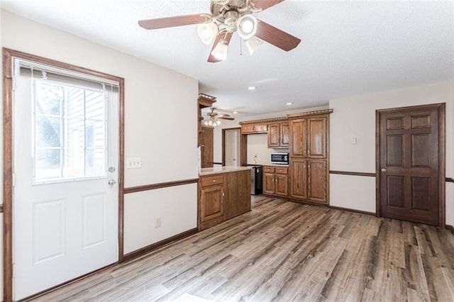 kitchen featuring built in microwave, ceiling fan, black dishwasher, and light hardwood / wood-style flooring