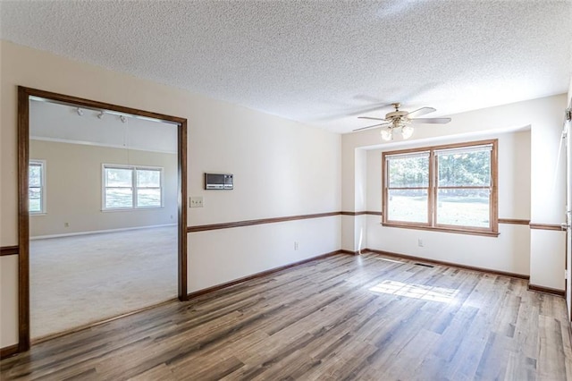 unfurnished room with ceiling fan, plenty of natural light, light hardwood / wood-style flooring, and a textured ceiling