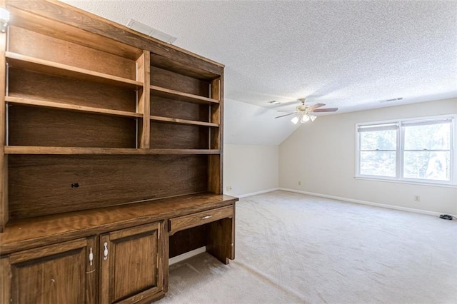 unfurnished office featuring light carpet, ceiling fan, vaulted ceiling, and a textured ceiling