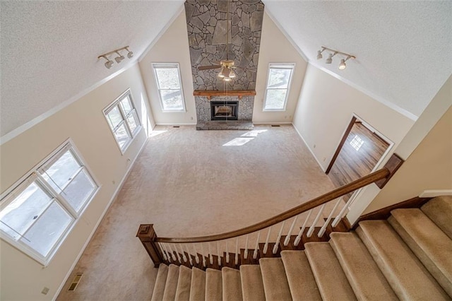 unfurnished living room featuring light colored carpet, a fireplace, high vaulted ceiling, and a textured ceiling