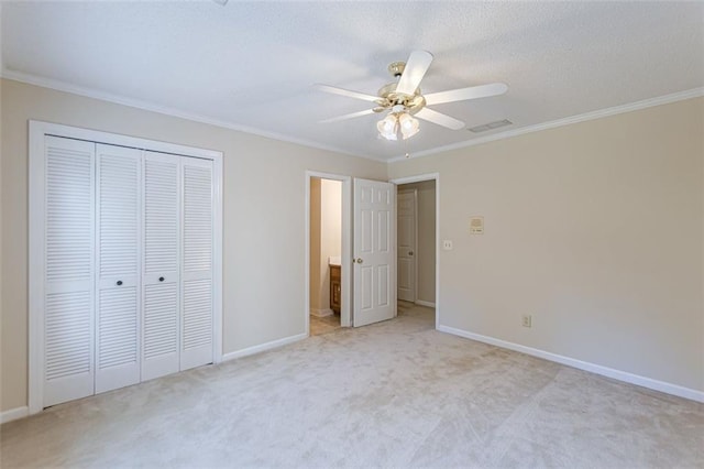 unfurnished bedroom with ornamental molding, light carpet, ceiling fan, and a closet