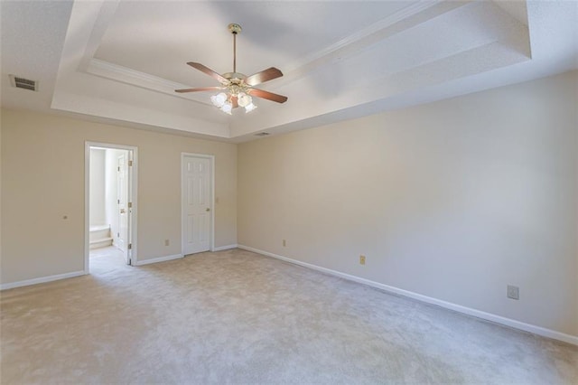 interior space with ceiling fan, light colored carpet, and a tray ceiling