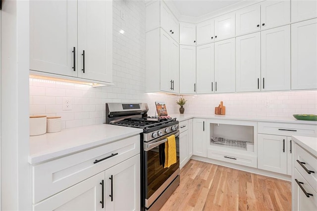 kitchen with gas range, white cabinetry, light countertops, and light wood-style floors