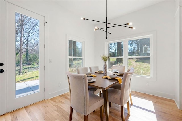 dining room with a notable chandelier, baseboards, and light wood-style floors