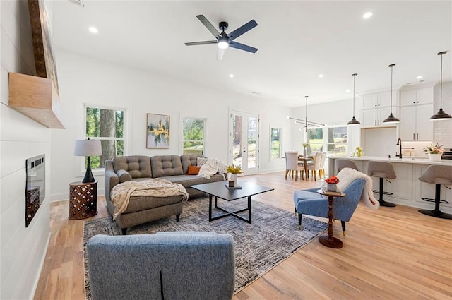 living area with light wood-type flooring, a ceiling fan, recessed lighting, a fireplace, and baseboards