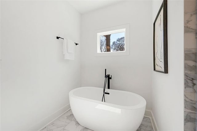 bathroom with a soaking tub, marble finish floor, and baseboards