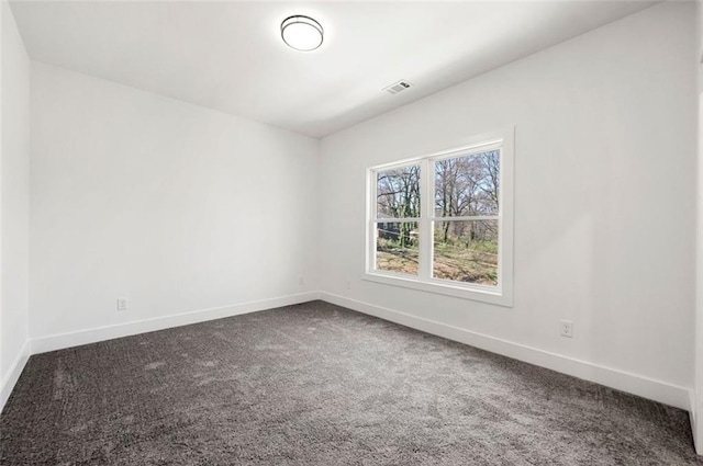 spare room featuring baseboards, visible vents, and dark carpet