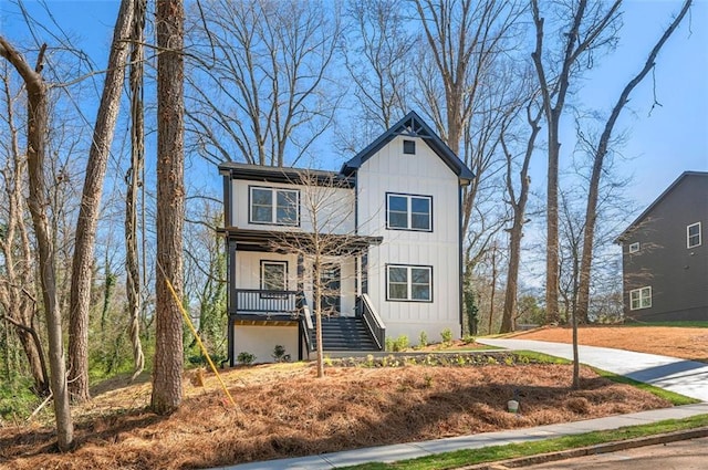 view of front of house with a porch, stairs, driveway, and board and batten siding