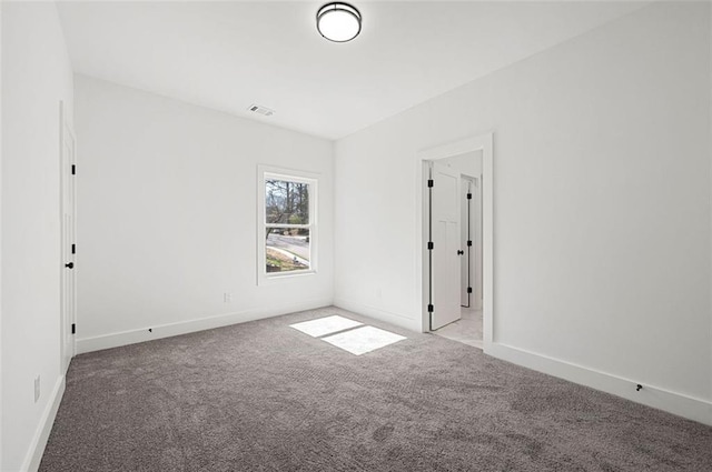 spare room with carpet flooring, visible vents, and baseboards