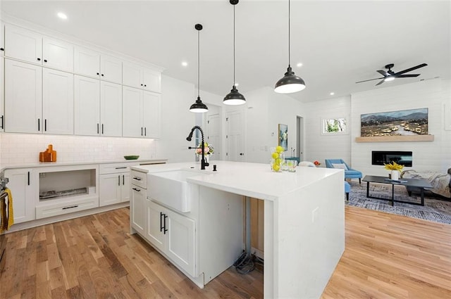 kitchen featuring a sink, open floor plan, light wood-style floors, light countertops, and ceiling fan