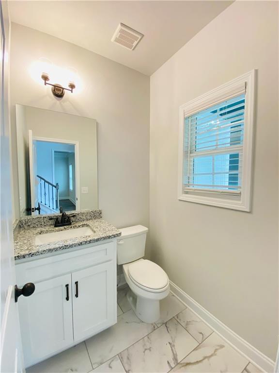 1540 Ox Bridge Ct, Lawrenceville, GA 30043 - half bathroom featuring marble finish floors, vanity, toilet, and baseboards