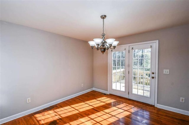 unfurnished dining area featuring wood-type flooring and an inviting chandelier