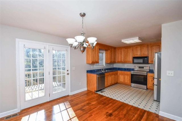 kitchen featuring hanging light fixtures, stainless steel appliances, light wood-type flooring, and a notable chandelier