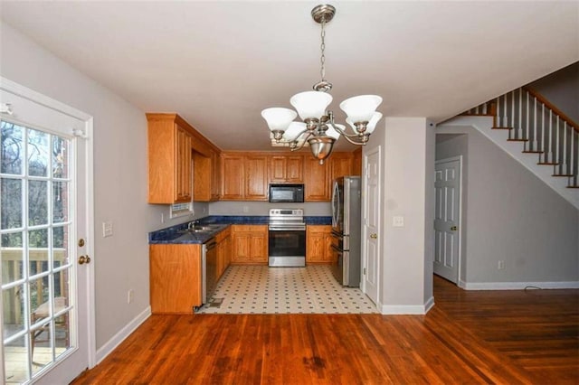 kitchen with sink, hanging light fixtures, an inviting chandelier, appliances with stainless steel finishes, and light wood-type flooring