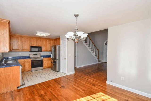 kitchen featuring sink, stainless steel appliances, an inviting chandelier, light hardwood / wood-style flooring, and pendant lighting