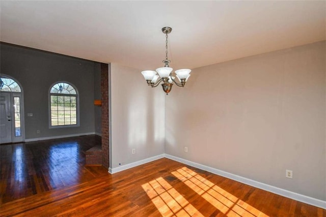 spare room featuring dark hardwood / wood-style flooring and an inviting chandelier