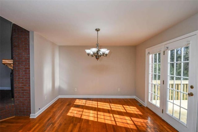 unfurnished dining area featuring dark hardwood / wood-style floors and an inviting chandelier