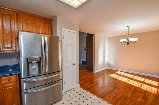 kitchen with stainless steel fridge with ice dispenser, light wood-type flooring, and an inviting chandelier