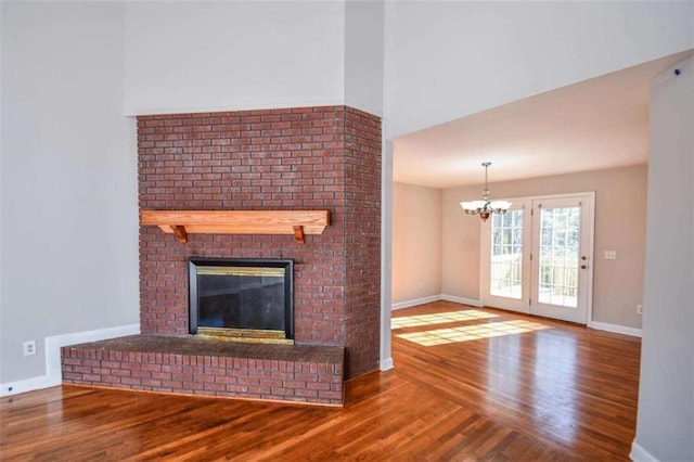 unfurnished living room featuring hardwood / wood-style floors, a fireplace, and a chandelier