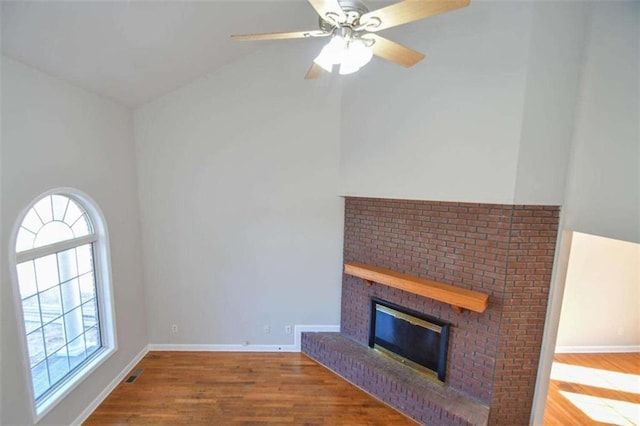 unfurnished living room with wood-type flooring, a brick fireplace, ceiling fan, and lofted ceiling