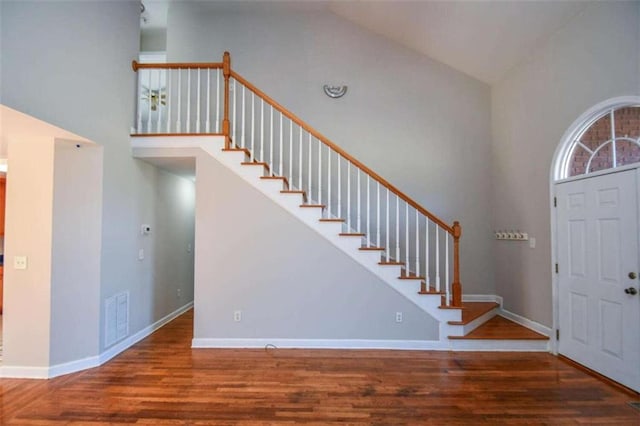 foyer entrance with high vaulted ceiling and wood-type flooring