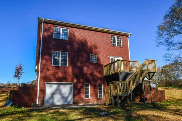 back of property featuring a garage, a deck, and a lawn