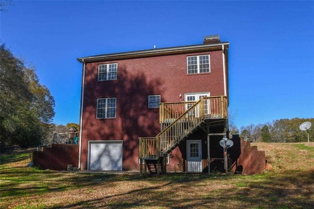 rear view of house featuring a yard, a deck, and a garage