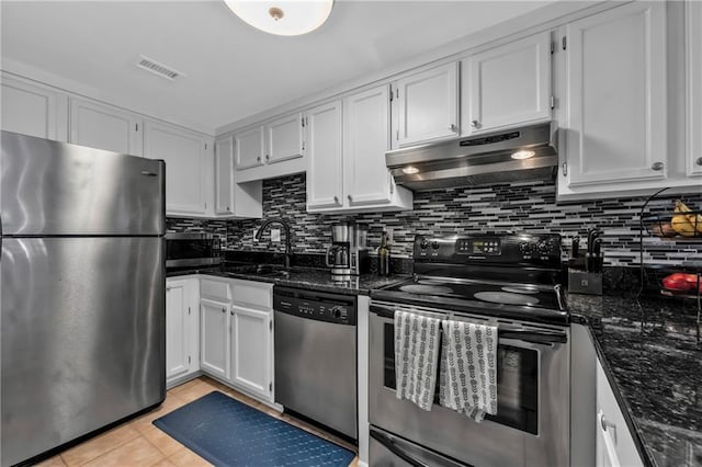 kitchen featuring appliances with stainless steel finishes, light tile patterned floors, white cabinets, and dark stone counters