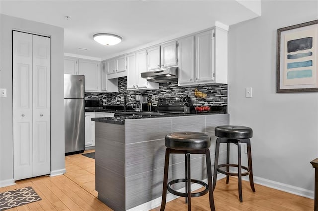 199 14th St NE Unit 2010, Atlanta, GA 30309 - kitchen with dark countertops, a peninsula, stainless steel appliances, under cabinet range hood, and backsplash